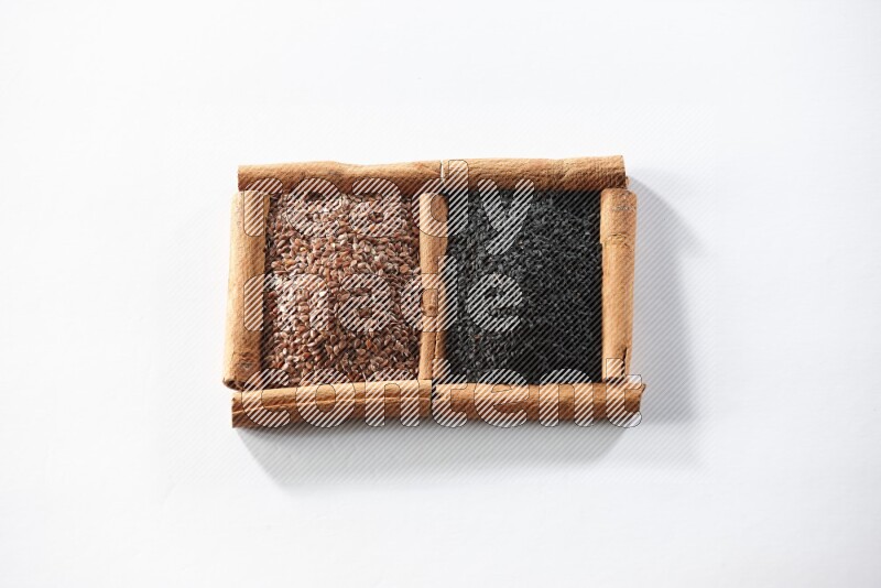 2 squares of cinnamon sticks full of flaxseeds and black seeds on white flooring