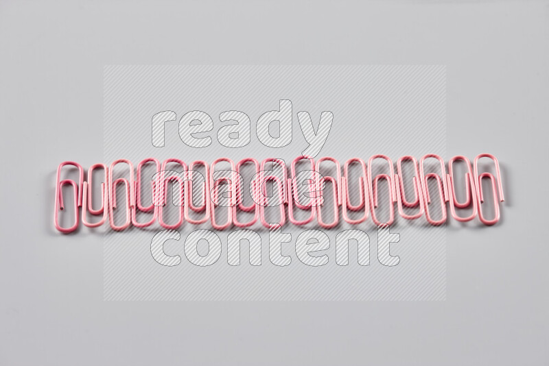 Pink paper clips isolated on a grey background