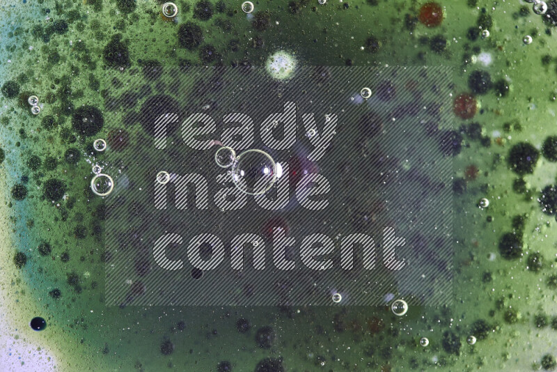 Close-ups of abstract red, green and blue watercolor drops on oil Surface on green background