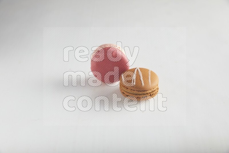 45º Shot of of two assorted Brown Irish Cream, and Pink Litchi Raspberry macarons on white background