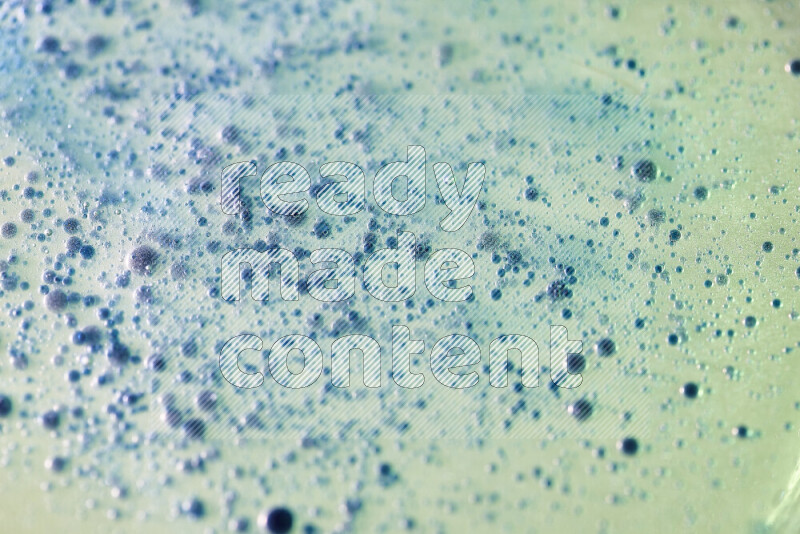 لقطات مقربة لقطرات ألوان مائية زرقاء على سطح الزيت على خلفية خضراء