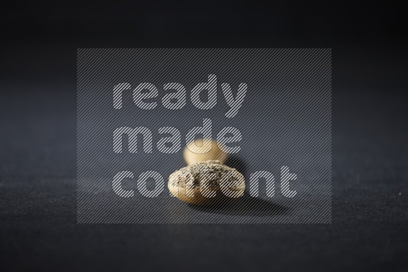 ملعقة خشبية ممتلئة ببودرة الهيل على خلفية سوداء