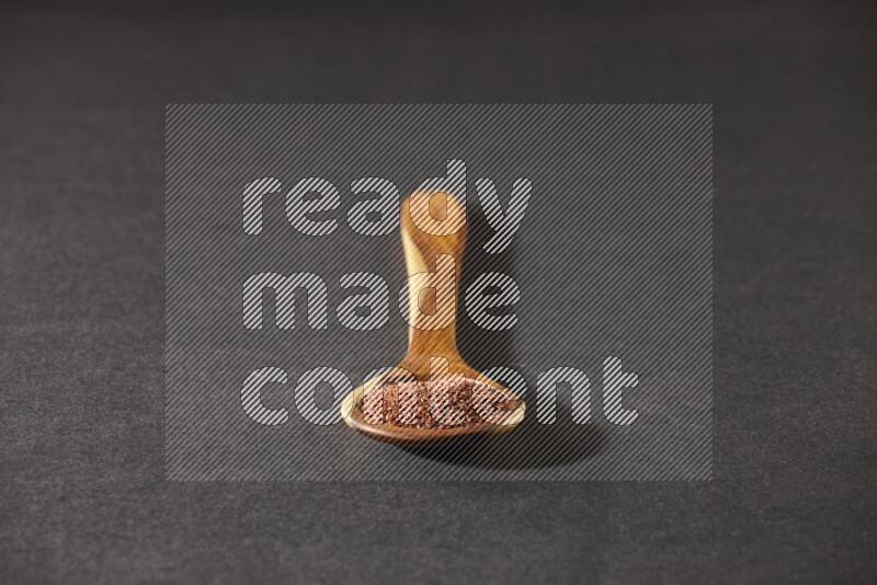 ملعقة خشبية كبيرة ممتلئة ببذور حب الرشاد علي خلفية سوداء