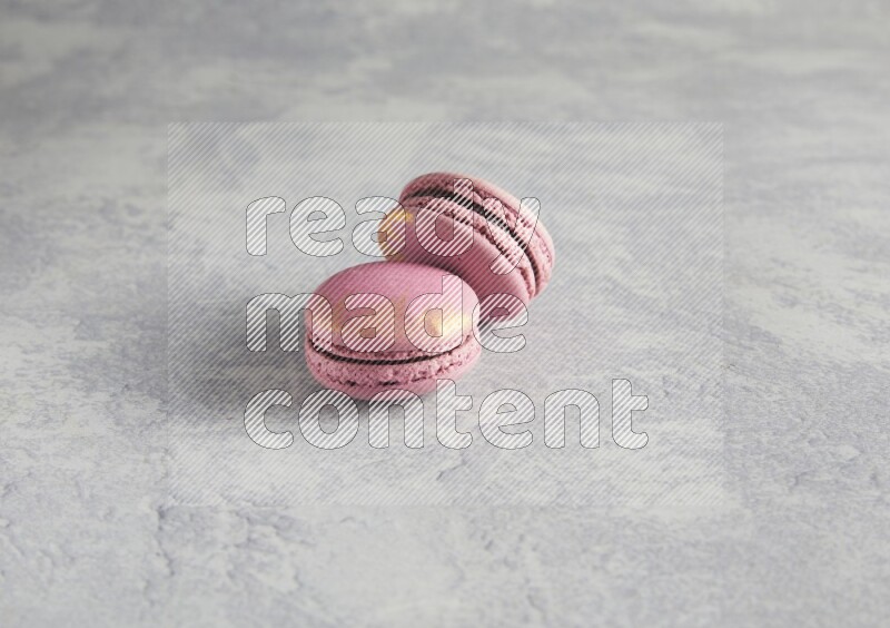 45º Shot of two Purple Strawberry macarons on white  marble background