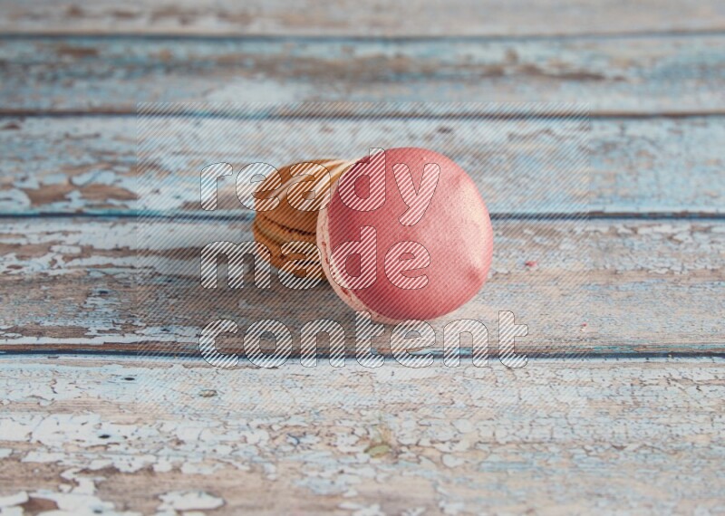 45º Shot of of two assorted Brown Irish Cream, and Pink Litchi Raspberry macarons on light blue background