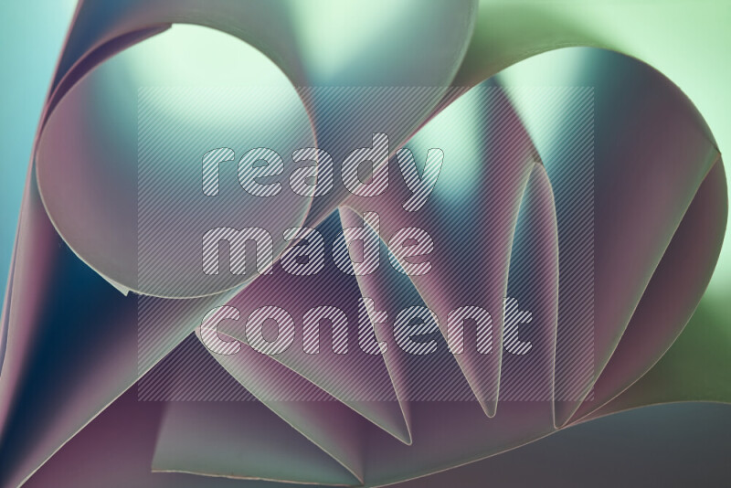 عرض فني لطيات الورق تخلق مزيج من الأشكال الهندسية، مضاءة بإضاءة ناعمة بدرجات اللون الأخضر والوردي