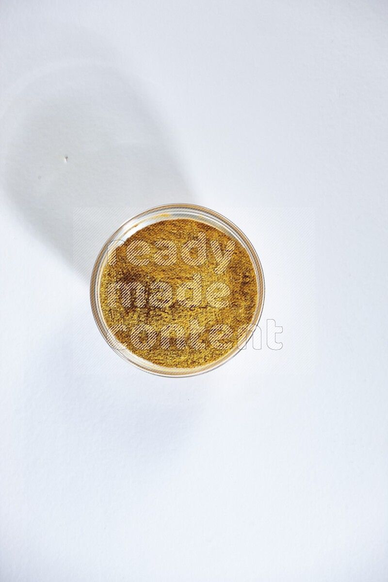 وعاء زجاجي ممتلئ ببودرة الكركم على خلفية بيضاء