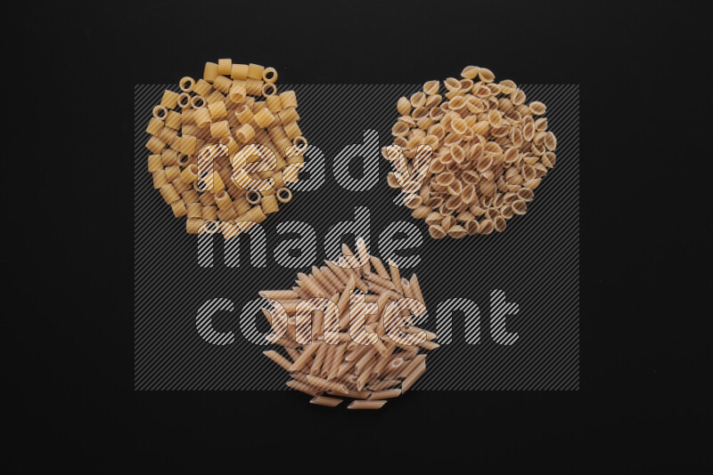 Different pasta types in bunches on black background