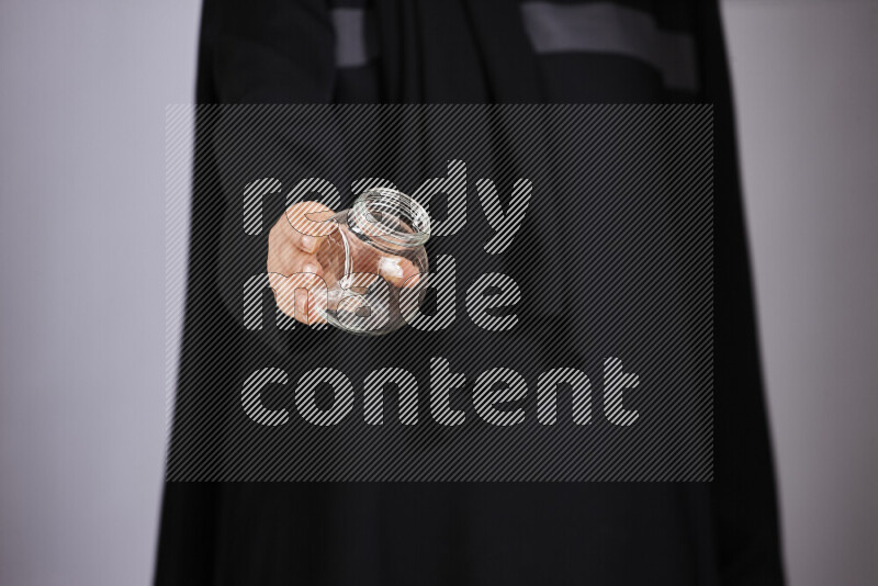 A woman in black abaya holding different glassware in different positions