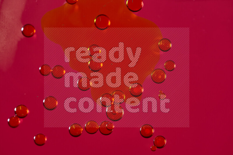 Close-ups of abstract yellow watercolor drops on oil Surface on red background