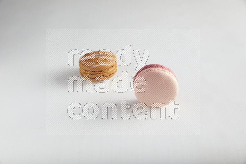45º Shot of of two assorted Brown Irish Cream, and Pink Litchi Raspberry macarons on white background