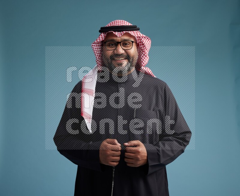 Saudi Man with shimag Standing Interacting with the camera on blue background