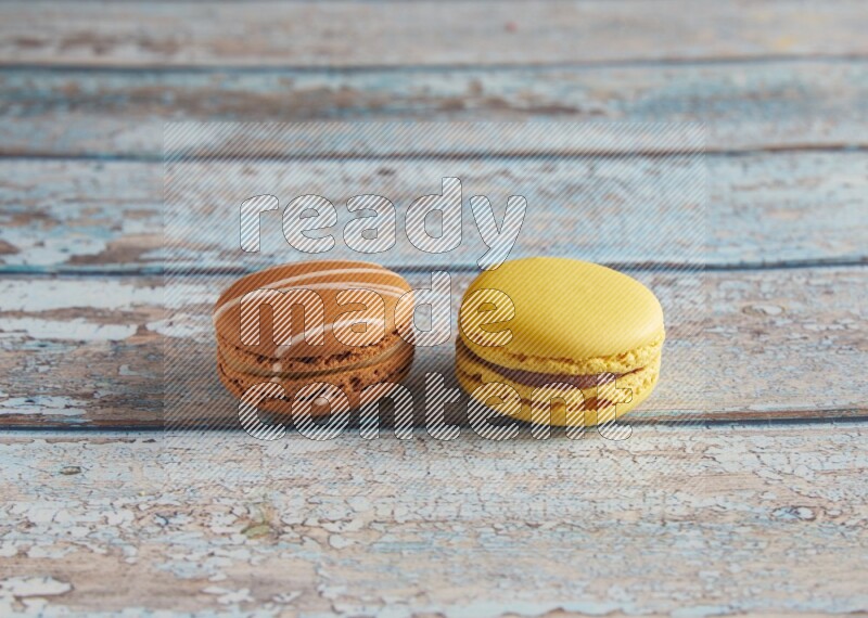 45º Shot of of two assorted Brown Irish Cream, and Yellow Lemon macarons on light blue background