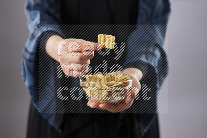 Woman in abaya holding different kinds of snacks in different positions