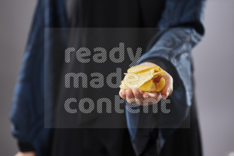 Woman in abaya holding different kinds of snacks in different positions
