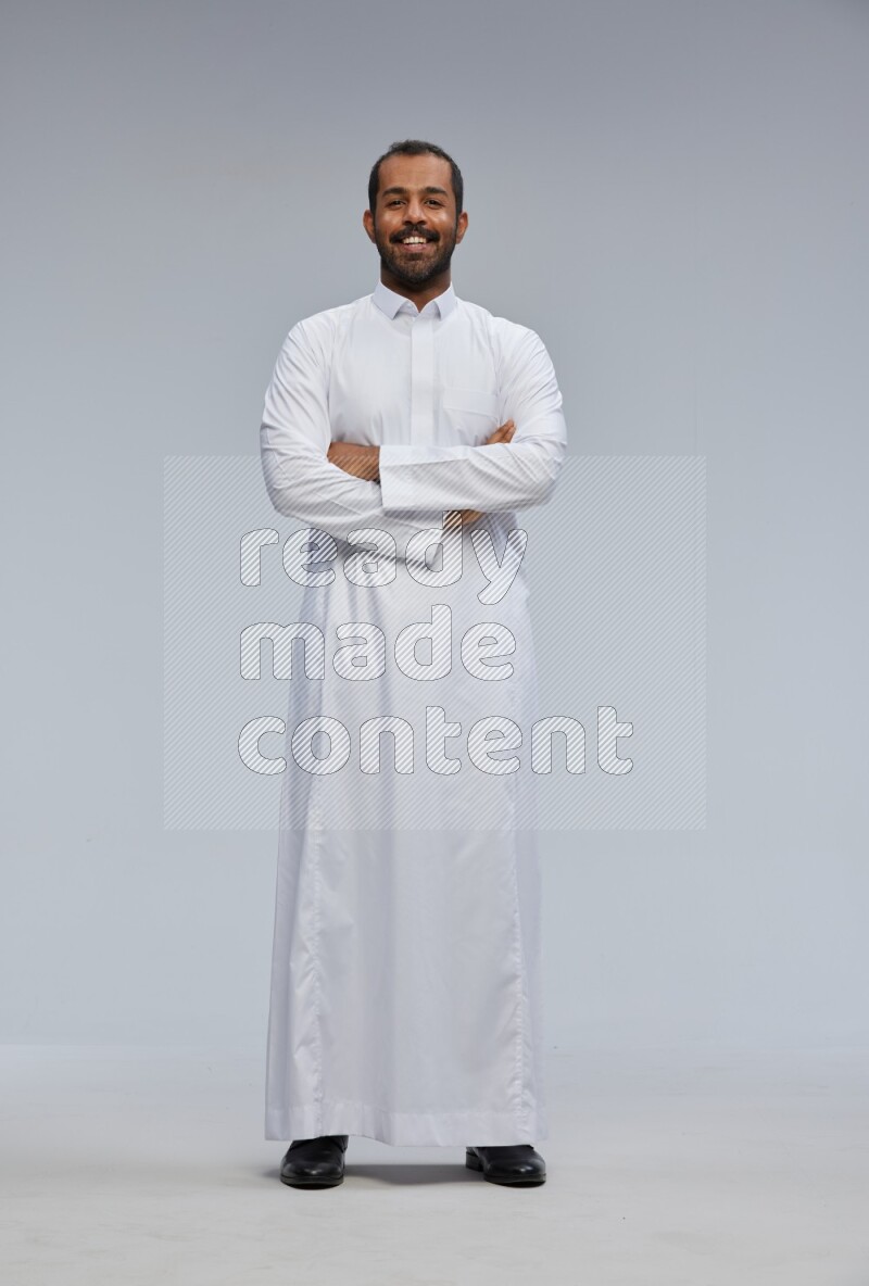 Saudi man wearing Thob standing with crossed arms on Gray background