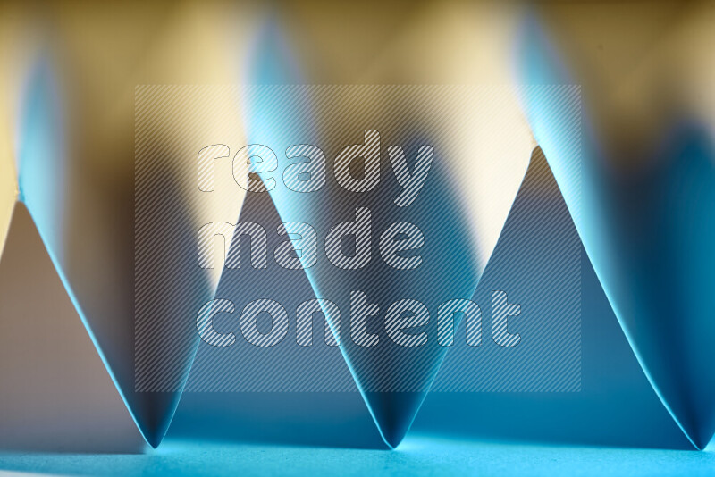 صورة مجردة مقربة تظهر طيات ورقية هندسية حادة بتدرجات اللون الأزرق مع درجات لونية دافئة