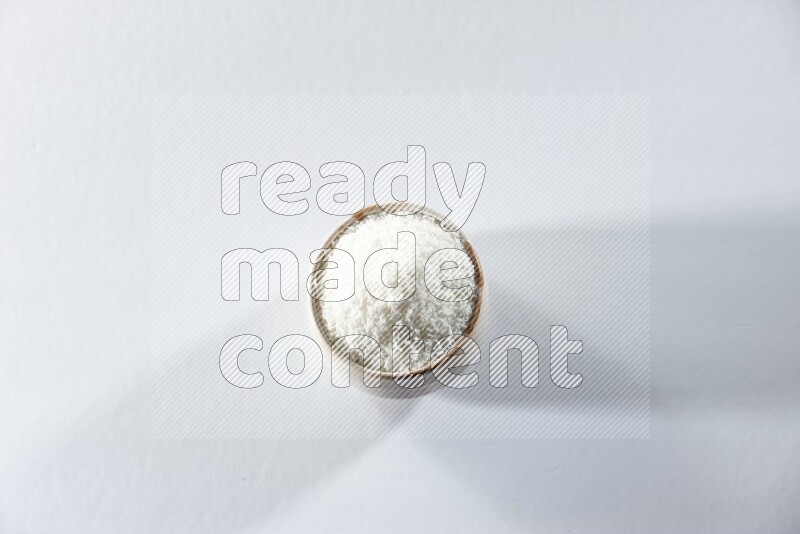 A beige ceramic bowl full of desiccated coconut on a white background in different angles