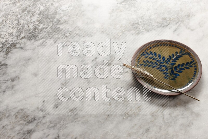 Wheat stalks on decorative pottery plate on grey marble background