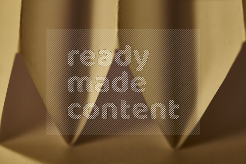 A close-up abstract image showing sharp geometric paper folds in warm gradients
