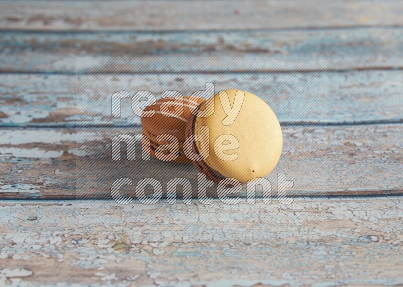 45º Shot of of two assorted Brown Irish Cream, and Yellow, and Brown Chai Latte macarons  on light blue background
