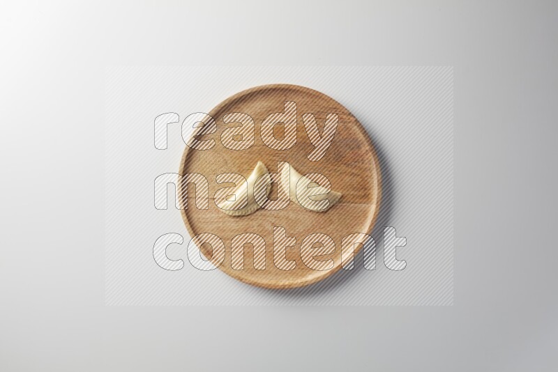 Two Sambosas on a wooden round plate on a white background