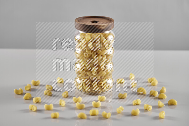 Raw pasta in a glass jar on light grey background