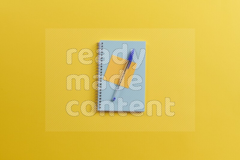 A blue notebook with different school supplies on yellow background