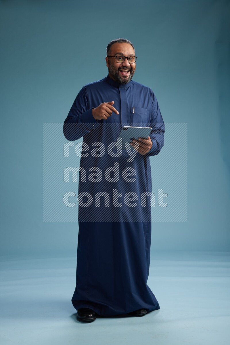 Saudi Man without shimag Standing working on tablet on blue background