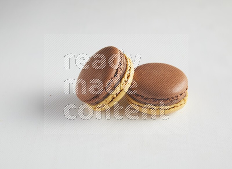 45º Shot of two Yellow and Brown Chai Latte macarons on white background