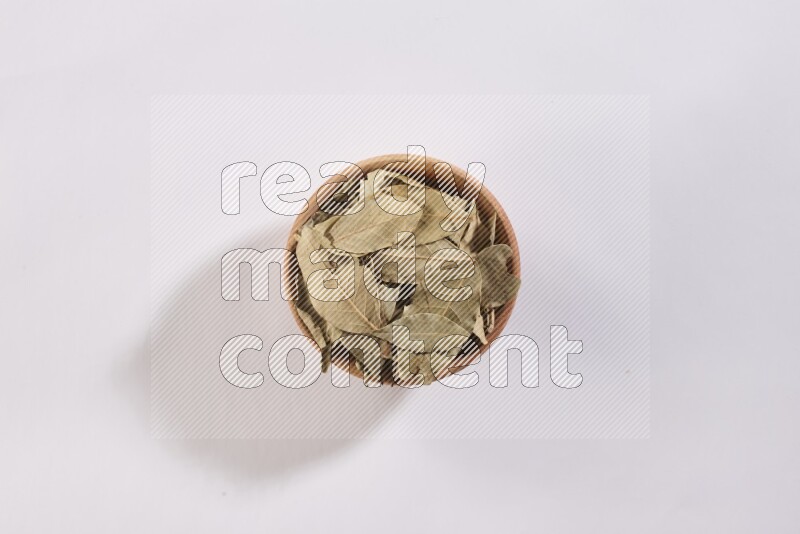 A wooden bowl filled with dried bay leaves on white flooring in different angles