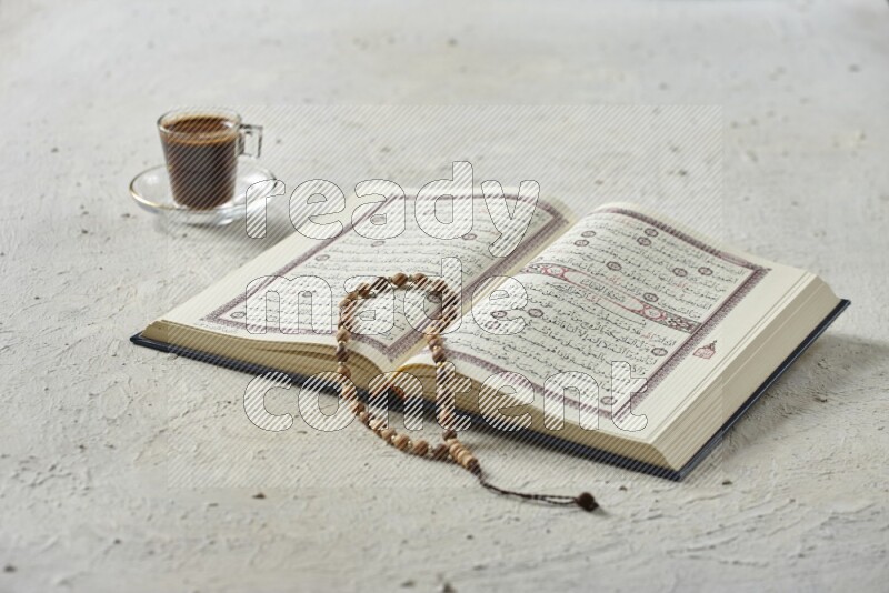 Quran with dates, prayer beads and different drinks all placed on textured white background