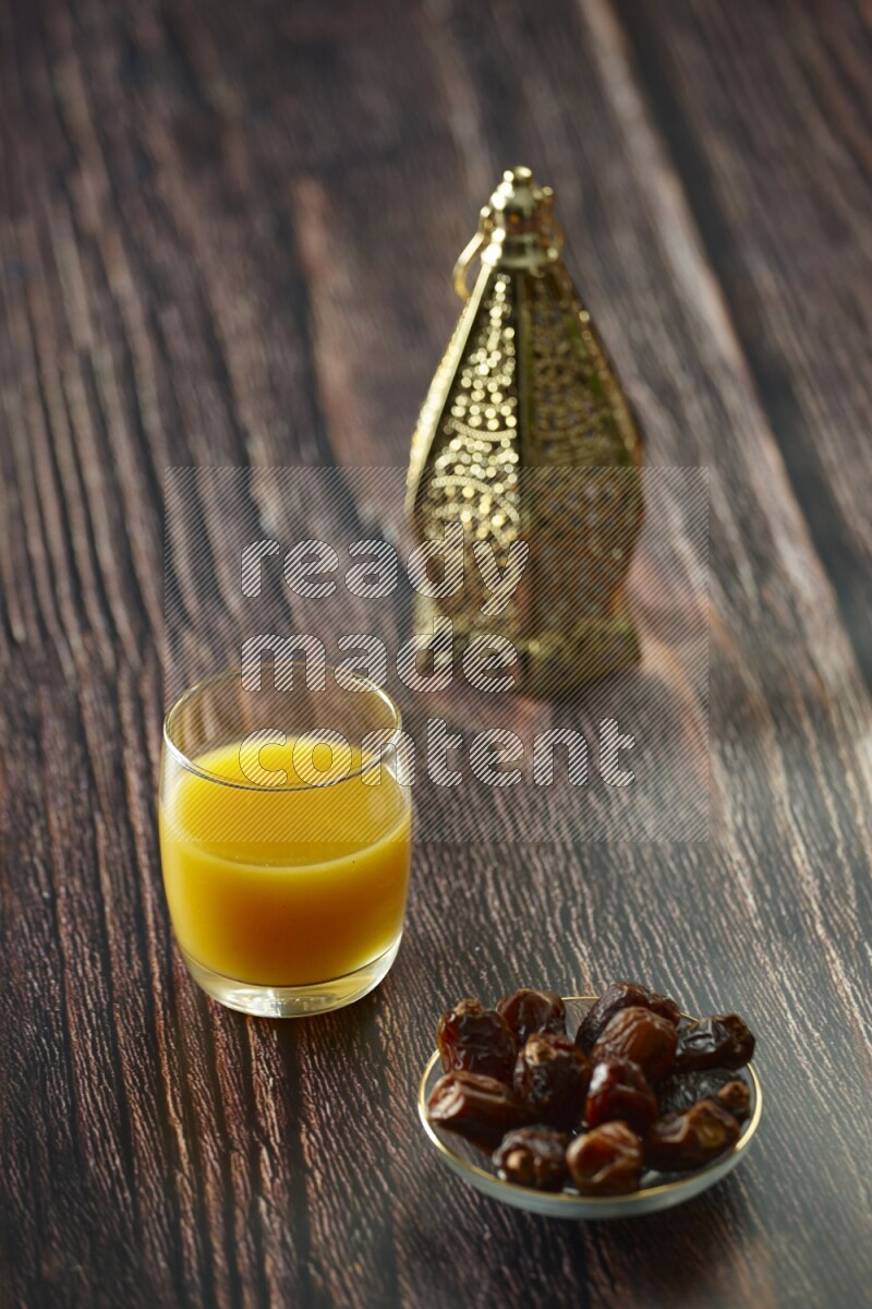 A golden lantern with different drinks, dates, nuts, prayer beads and quran on brown wooden background