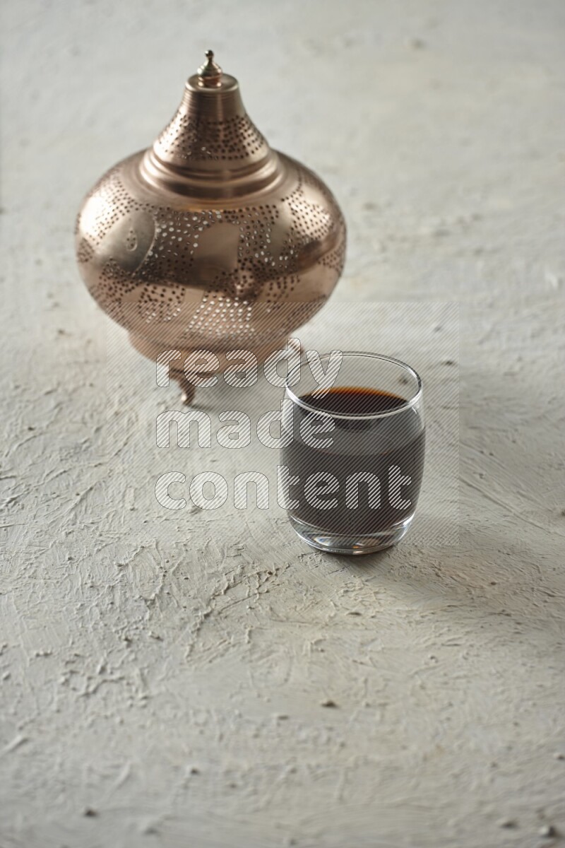 A golden lantern with different drinks, dates, nuts, prayer beads and quran on textured white background