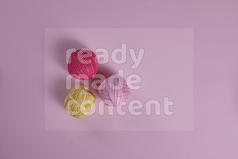 A yellow and pink collection of sewing and tailoring tools arranged on a pink background