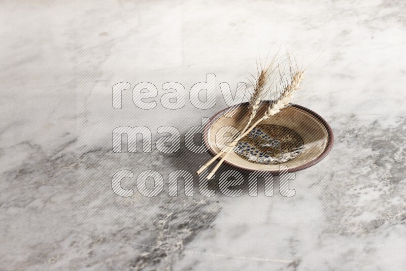 Wheat stalks on decorative pottery plate on grey marble background