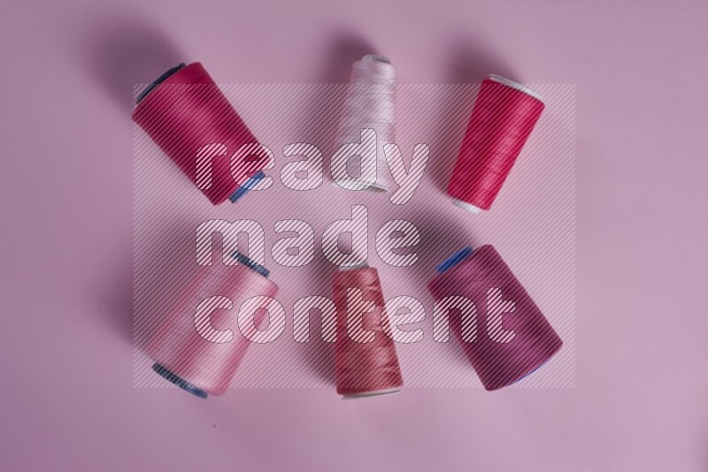 A pink collection of sewing and tailoring tools arranged on a pink background