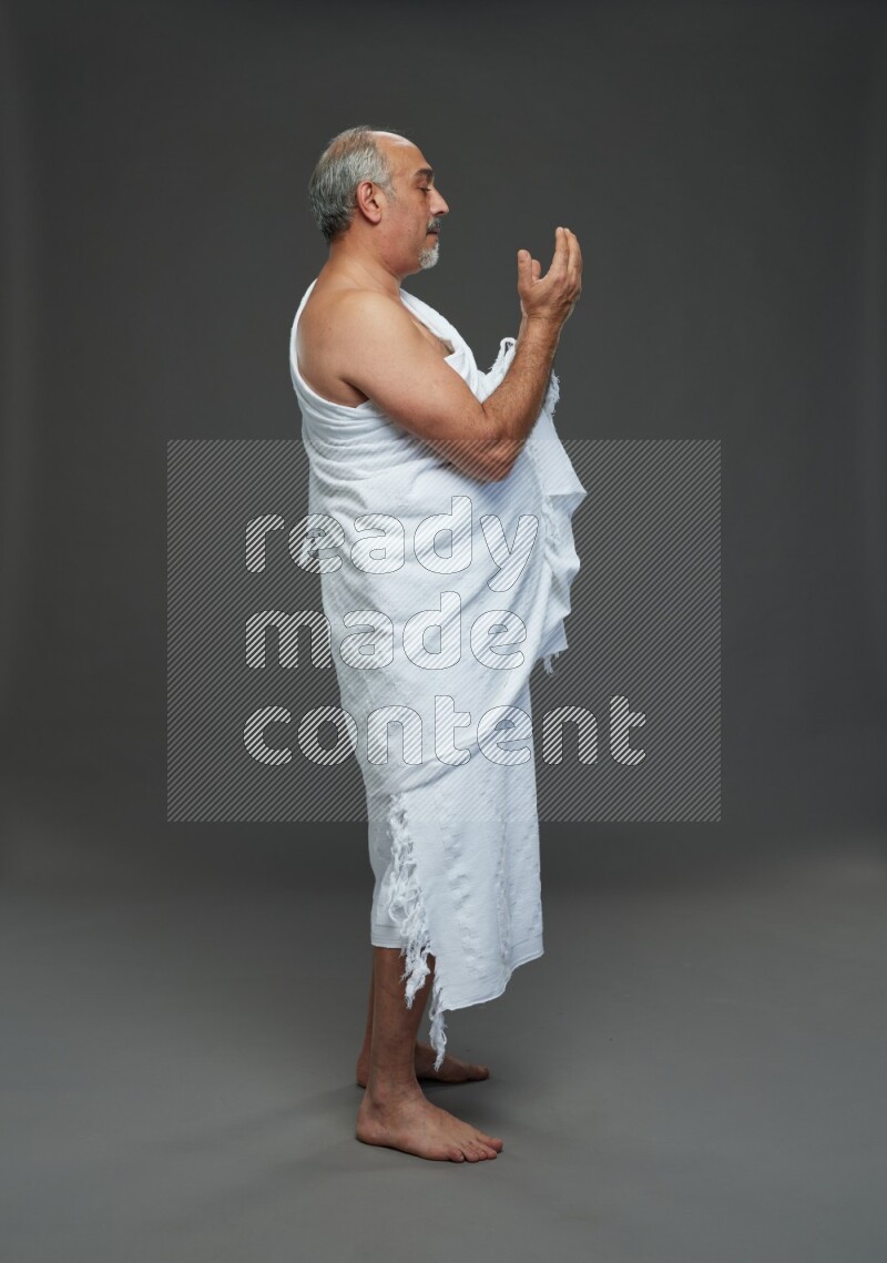 A man wearing Ehram Standing dua'a on gray background
