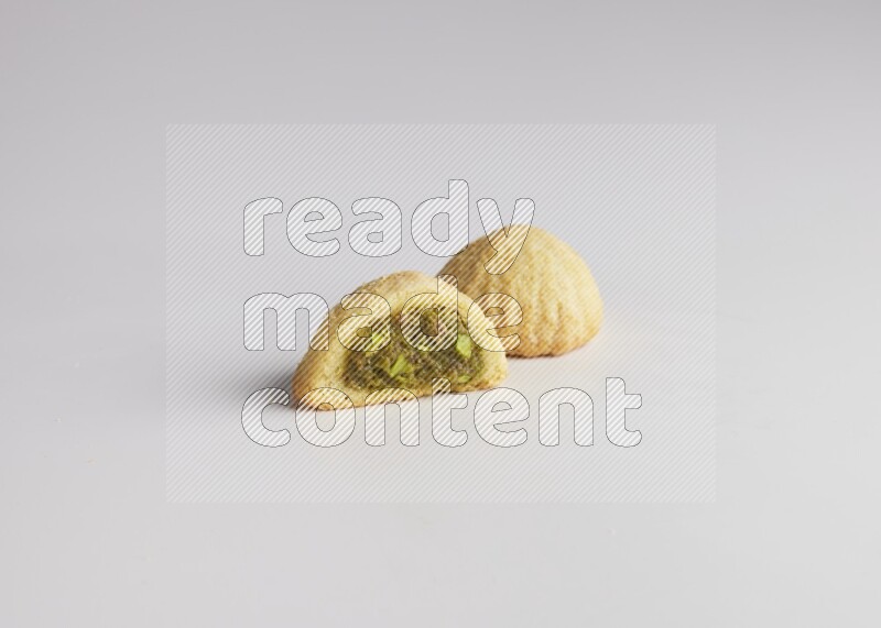 Two Pieces of Maamoul filled with pistachio paste  one of them is cut direct on white background