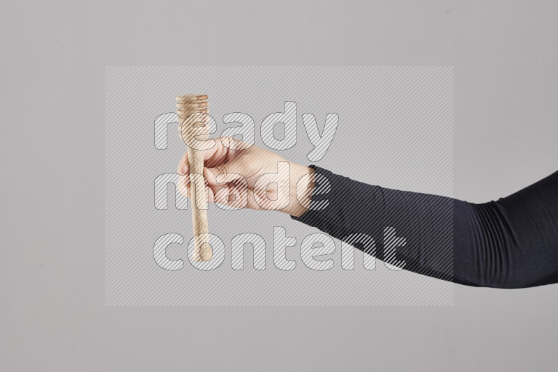 امرأة ترتدي عباءة سوداء تحمل أدوات خشبية مختلفة في أوضاع متعددة