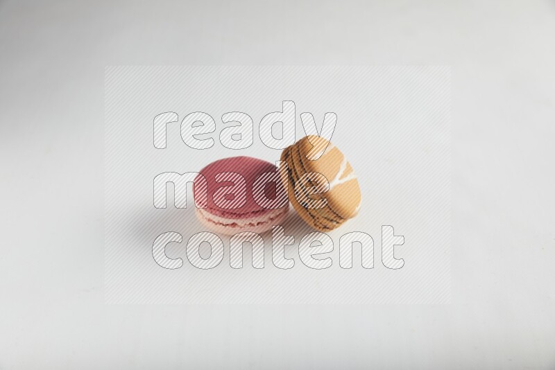 45º Shot of of two assorted Brown Irish Cream, and Pink Litchi Raspberry macarons on white background