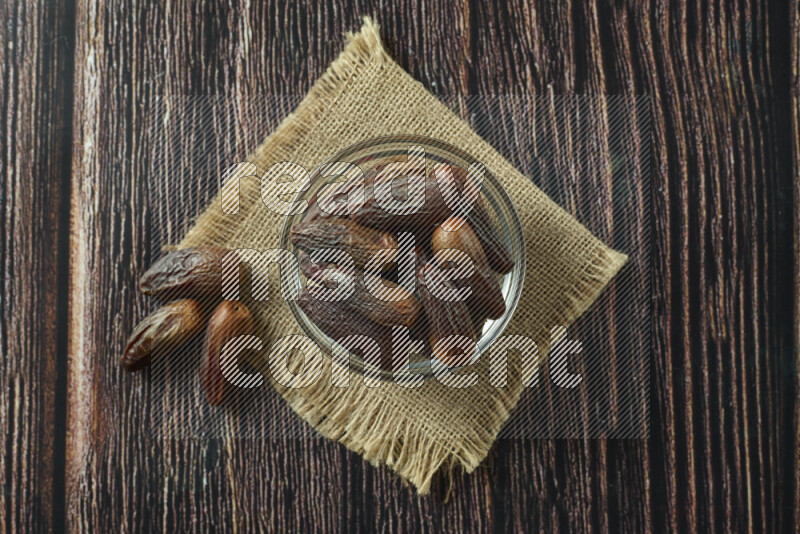 Dates in different bowls (wooden, pottery and glass) on wooden background