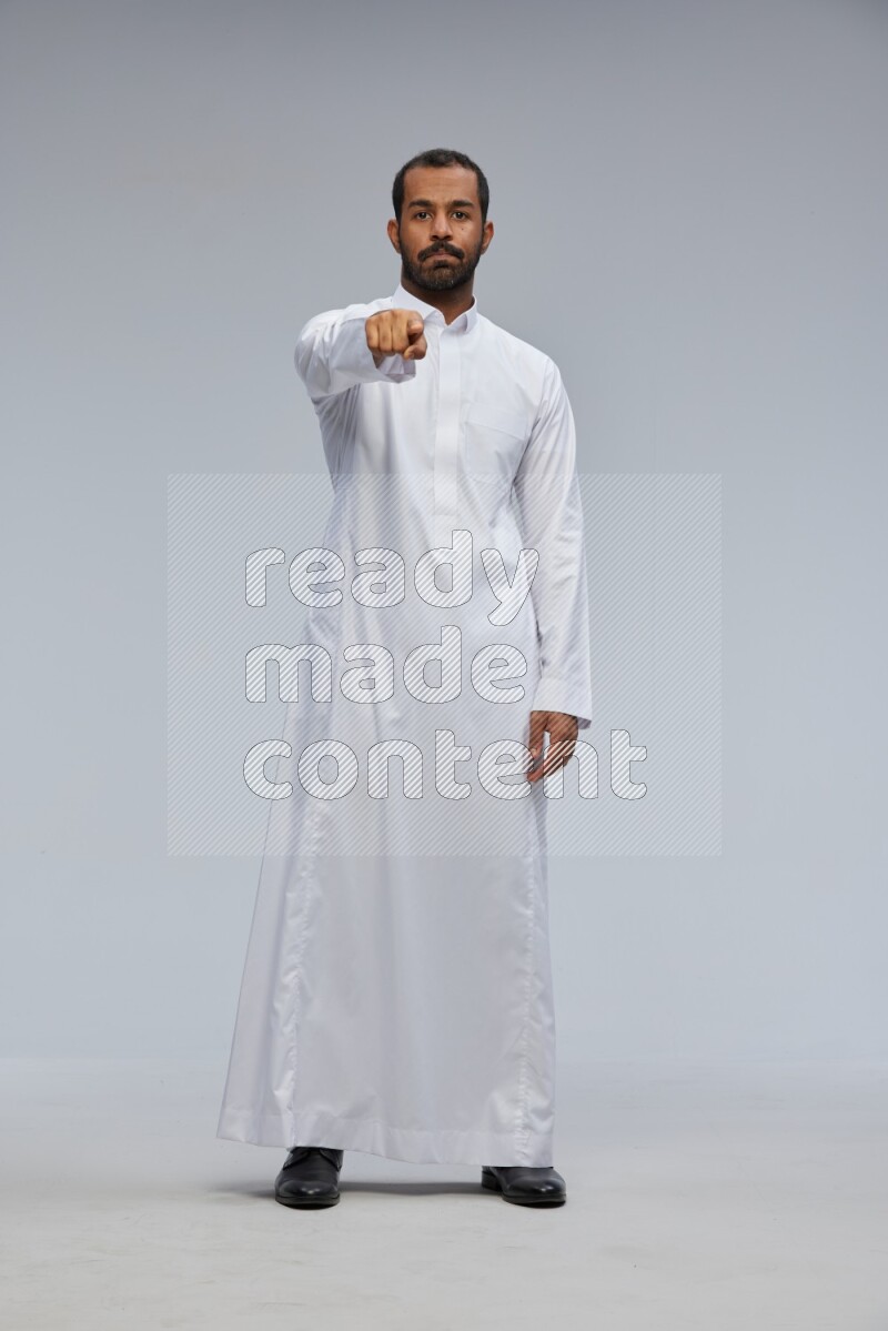 Saudi man Wearing Thob standing interacting with the camera on Gray background