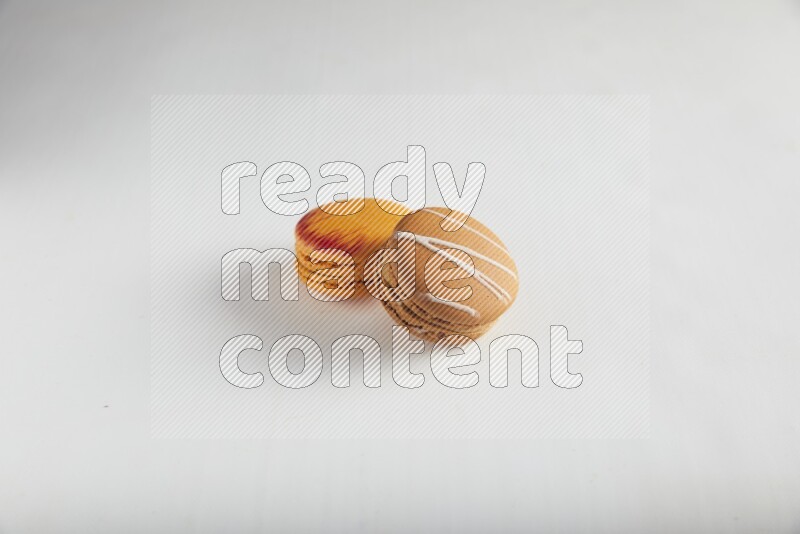 45º Shot of of two assorted Brown Irish Cream, and Orange Exotic macarons on white background