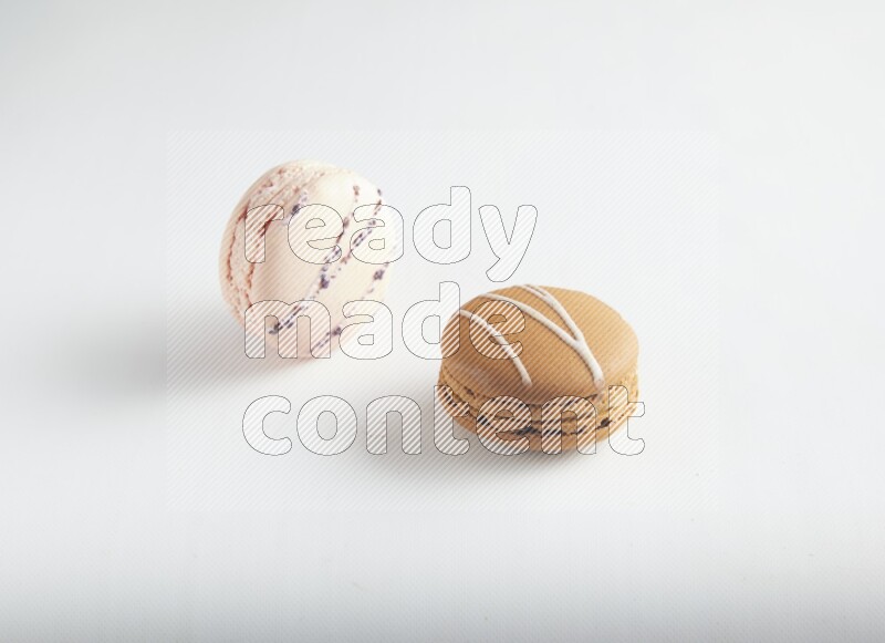 45º Shot of of two assorted Brown Irish Cream, and pink orange blossom macarons on white background