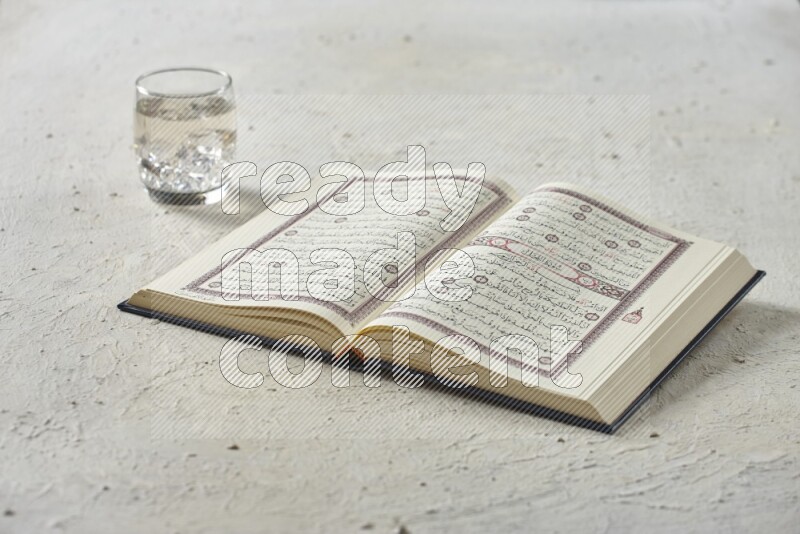 Quran with dates, prayer beads and different drinks all placed on textured white background