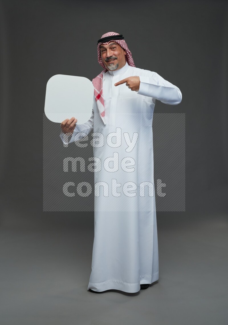Saudi man with shomag Standing holding social media sing on gray background