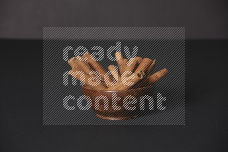 Cinnamon Sticks in a wooden bowl on black background