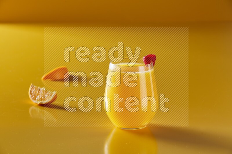 glass of orange juice with berry on yellow background