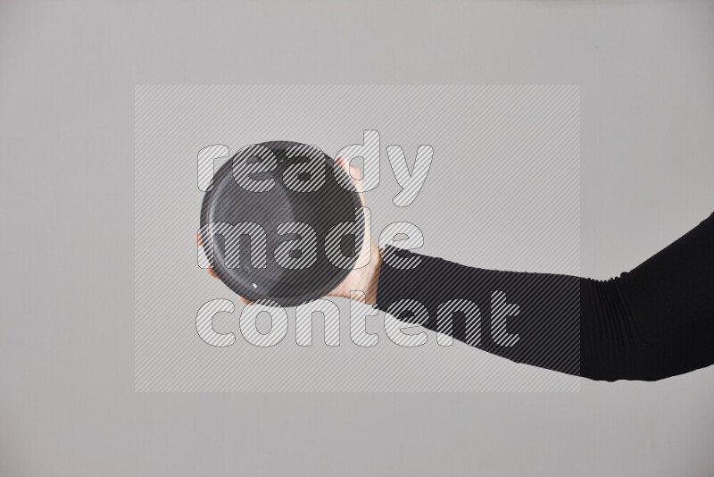 A woman in black abaya holding different pottery essentials in different positions